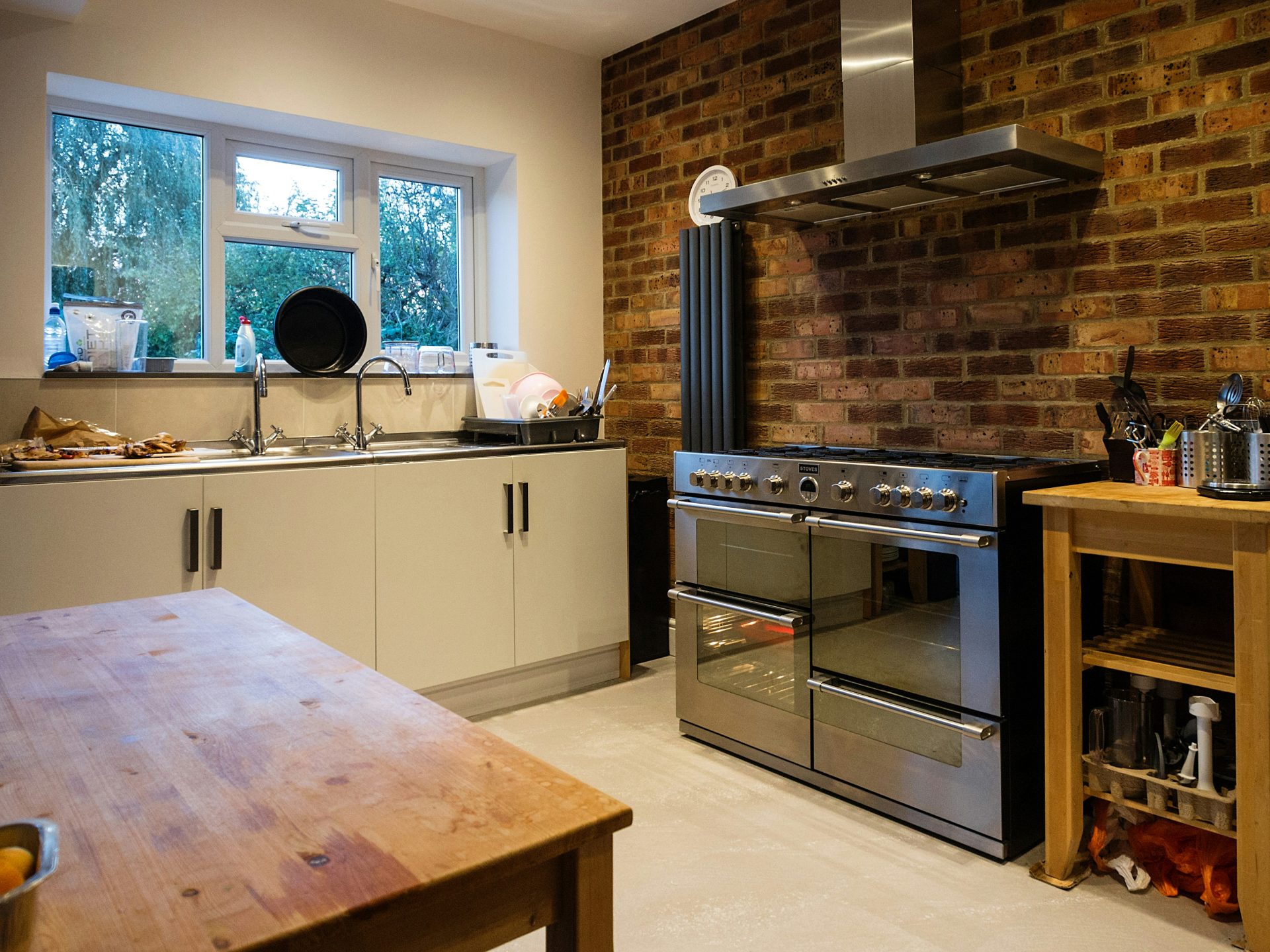 Here is a caption for the image: a kitchen with stainless steel appliances and exposed brick.