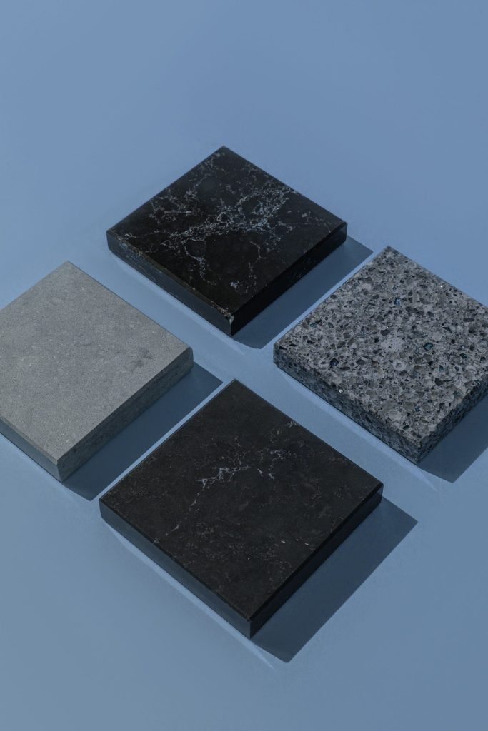 Four textured stone tiles on a blue background with shadows and angles.